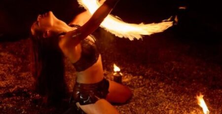 Fire dancer performing with flaming fans at an outdoor event in Toronto