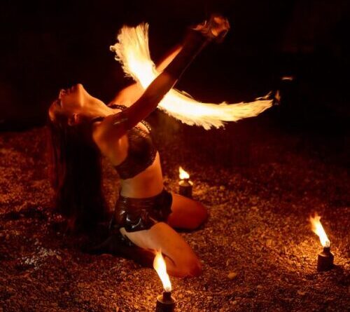 Fire dancer performing with flaming fans at an outdoor event in Toronto