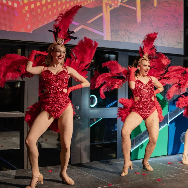 Professional showgirls performing in vibrant red feather costumes at a luxury corporate and private event in Toronto.