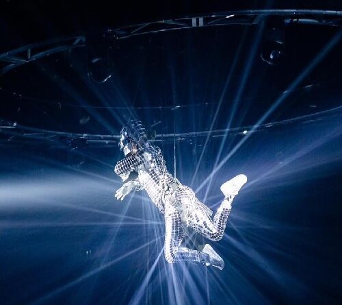 Mirror costume aerial performer suspended above a corporate event with dramatic lighting effects in Toronto.